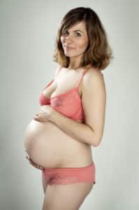 Babybauchshooting in Mannheimer Studio, Frau trägt rosa Unterwäsche.