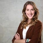 Bewerbungsbild von einer Frau vor grauer Wand mit struktur.