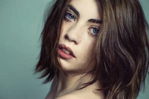 Portrait von einer frau mit blauen Augen und dunklen haaren im Fotostudio.